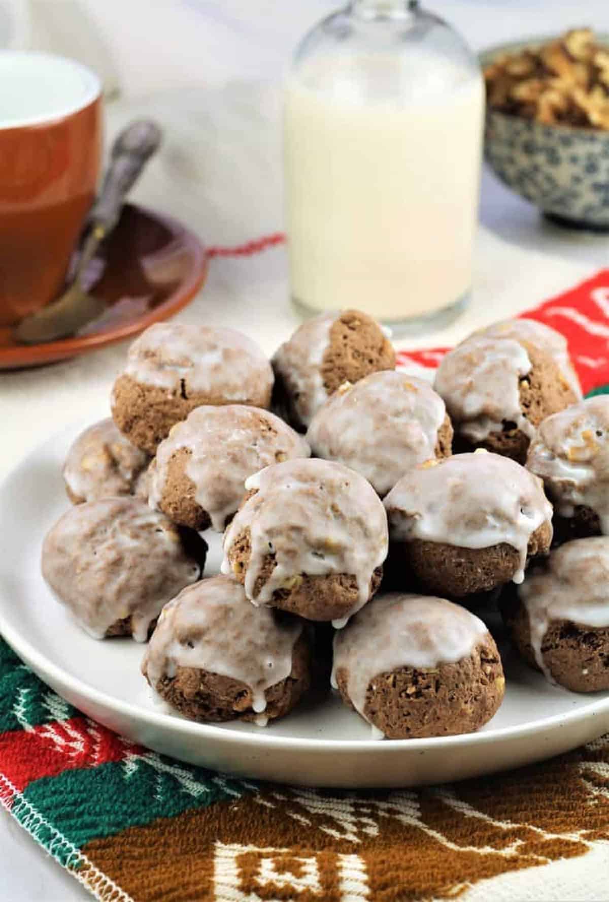 Tetù (Sicilian Chocolate Spice Cookies) Sicilian chocolate spice cookies (tetù) piled on plate next to bottle of milk and coffee cup.