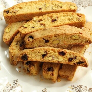 Pistachio cranberry biscotti with cornmeal piled on plate.