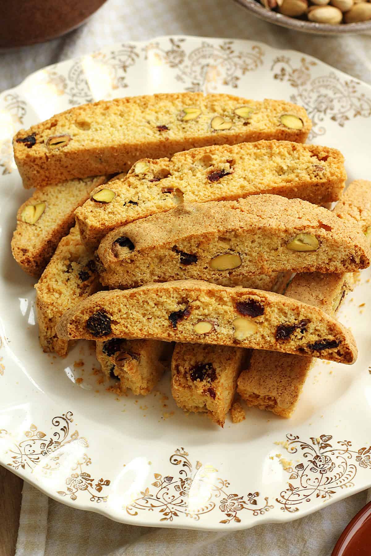 Pistachio cranberry biscotti with cornmeal piled on plate.
