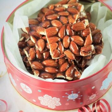 Sicilian almond torrone cut into squares in decorative Christmas tin.