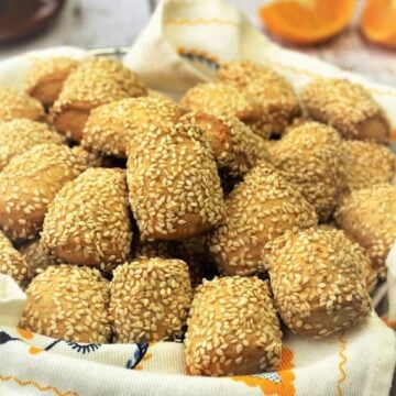Sicilian sesame seed cookies (reginelle) piled on dishcloth covered basket.