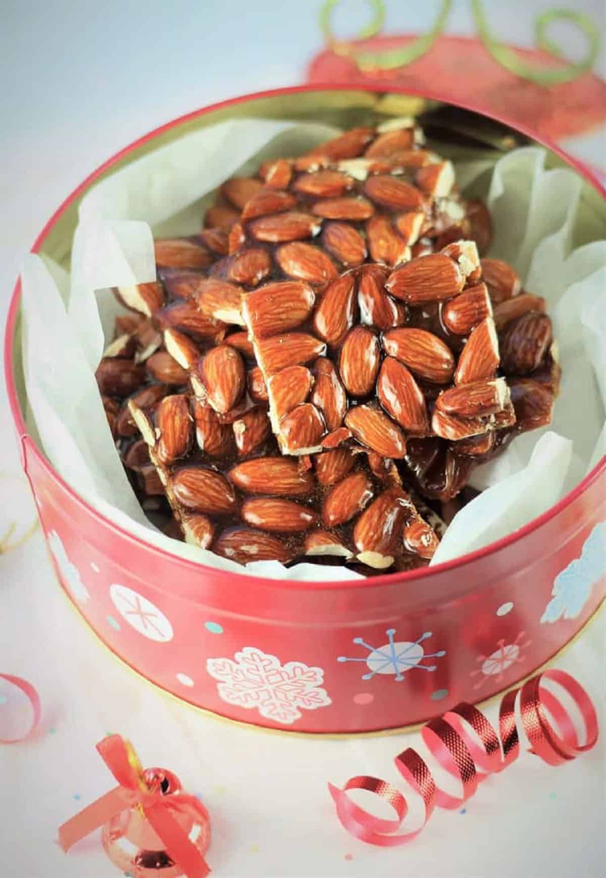 Sicilian almond torrone cut into squares in decorative Christmas tin.
