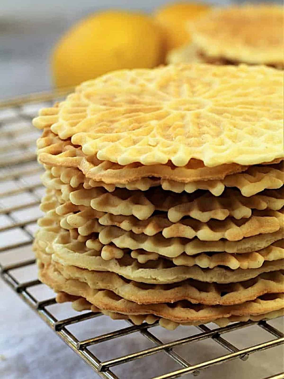 Pizzelle stacked on a wire rack.