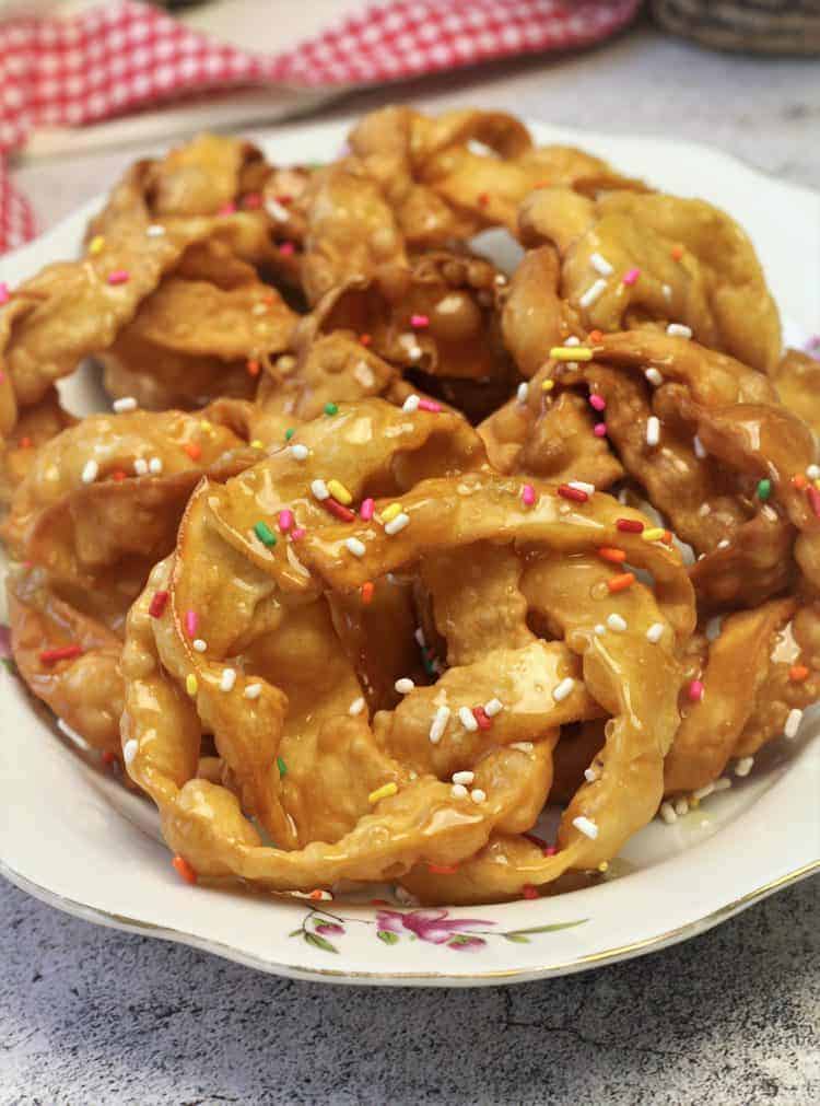 Braided pignolata drenched in honey on plate.