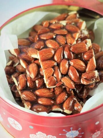 Almond croccante cut into squares in decorative tin.