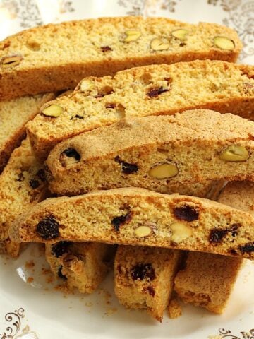 Pistachio cranberry biscotti with cornmeal piled on plate.