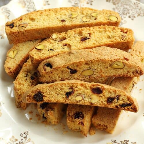 Pistachio cranberry biscotti with cornmeal piled on plate.