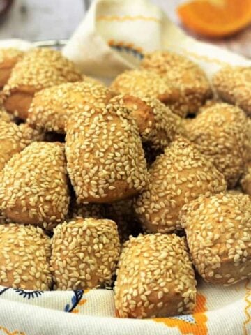 Reginelle cookies with sesame seeds piled on plate.