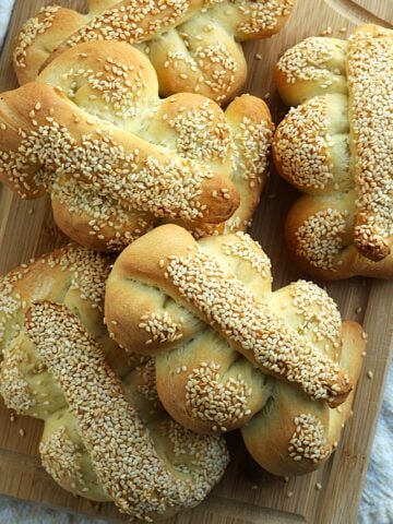 Sicilian Mafalda breads piled on wood board.