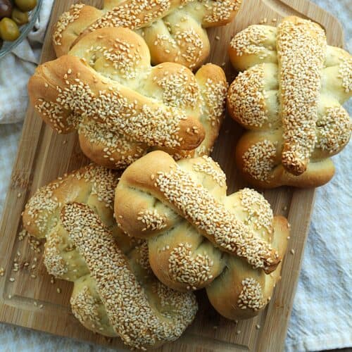 Sicilian Mafalda breads piled on wood board.