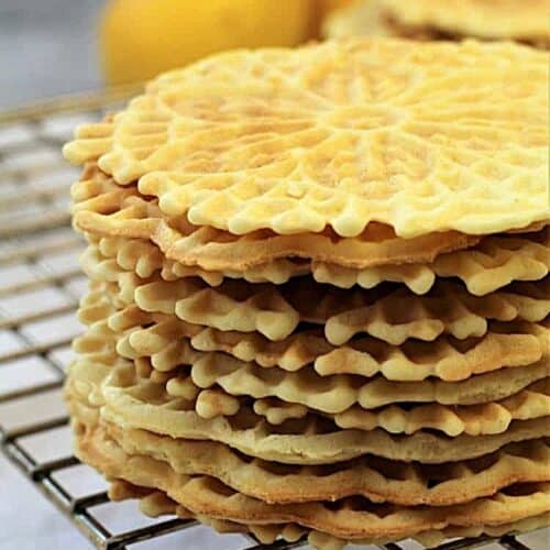 Italian waffle cookies stacked on wire rack.