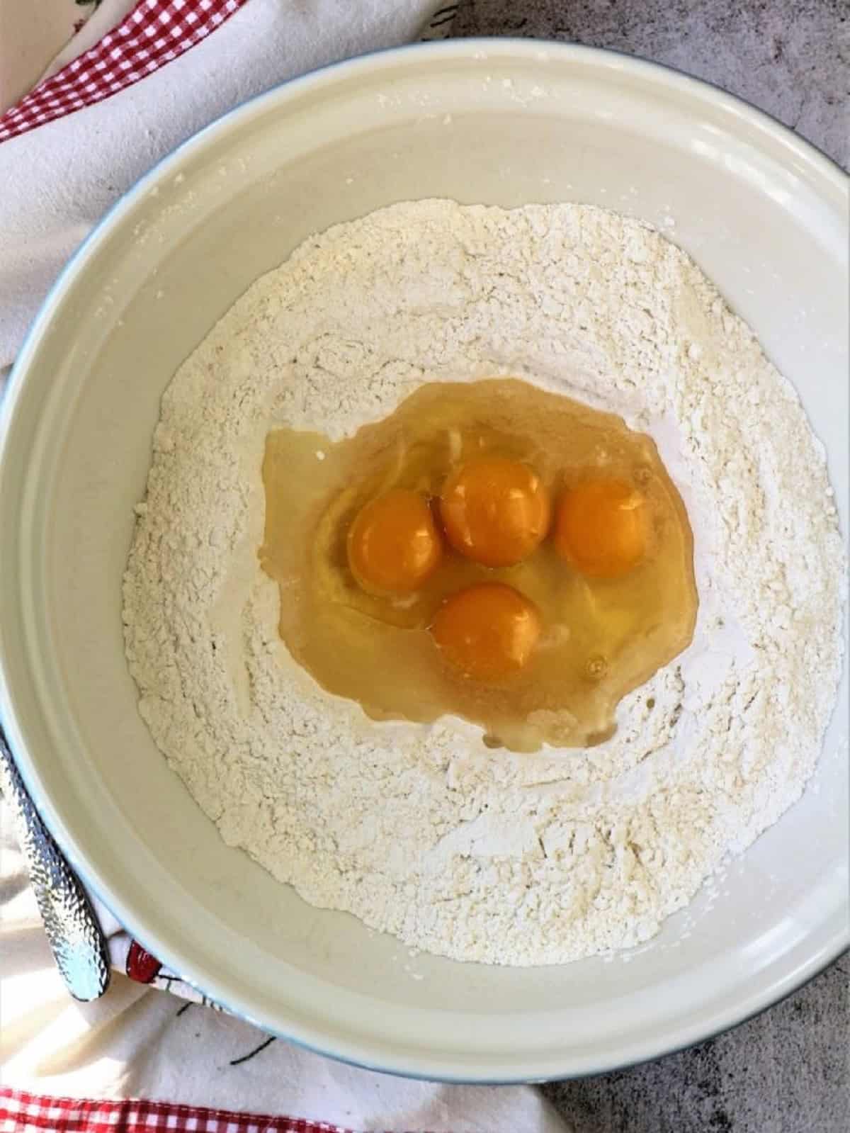 Whole eggs in bowl with dry ingredients for pignolata.