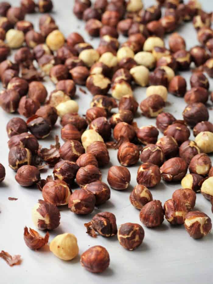 Whole roasted hazelnuts on baking sheet for cookie recipe.