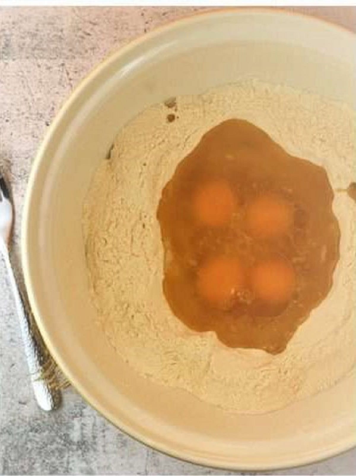 Dry ingredients with eggs in the center of bowl.