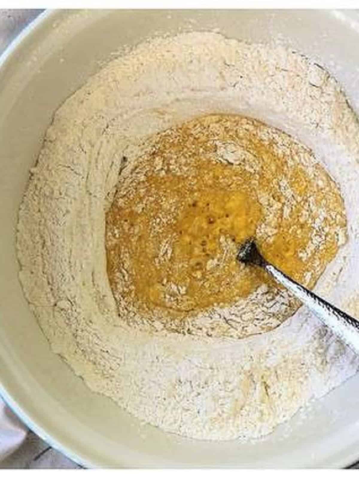 Beaten eggs in the center of bowl with dry ingredients for pignolata.