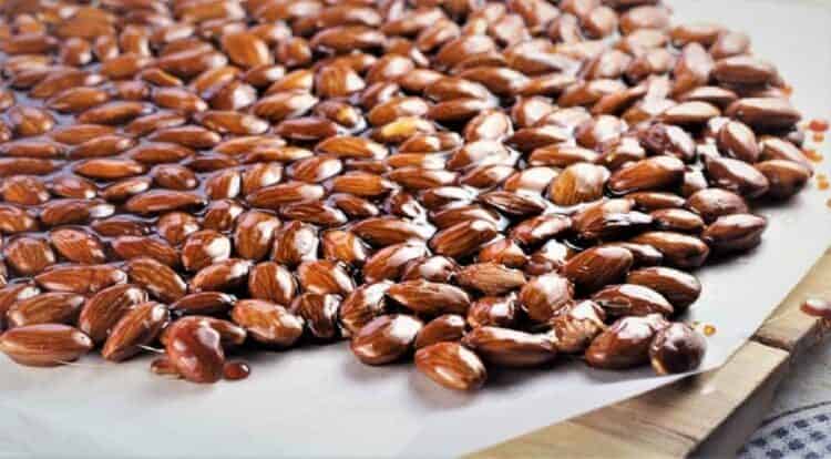 Sicilian almond torrone spread out on wood board covered in parchment paper.