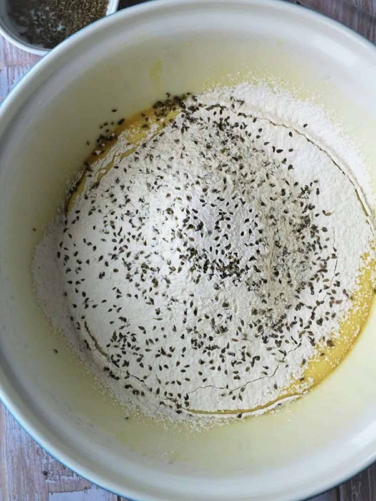 Anise seed scattered over flour in large bowl for biscotti recipe with anise.