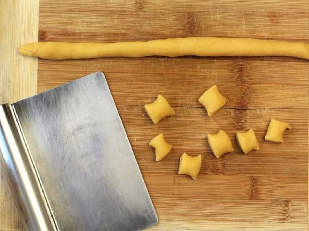 Pignolata dough shaped into a rope and cut into bite sized pieces.