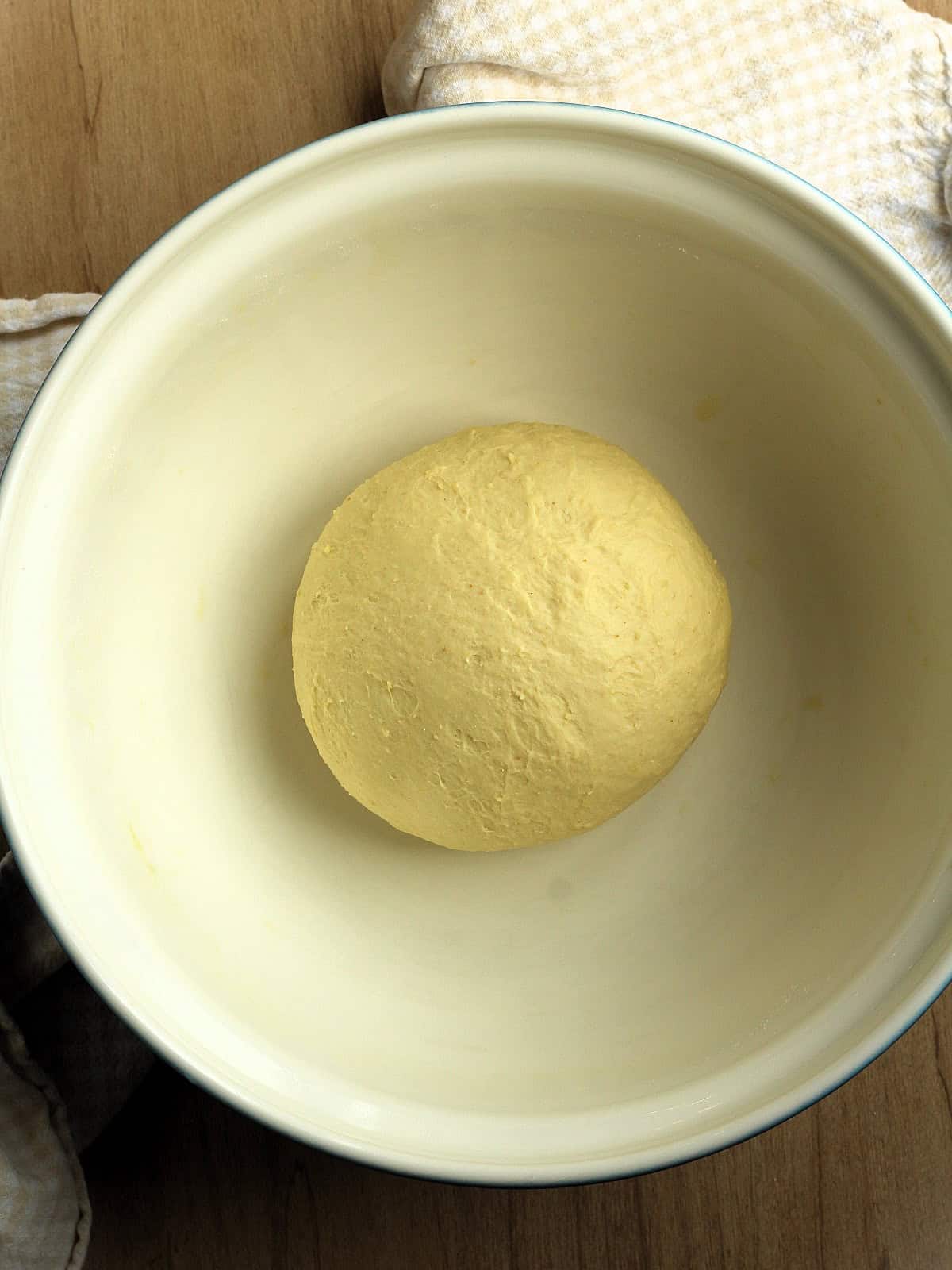 Semolina bread dough shaped into a ball in bowl.