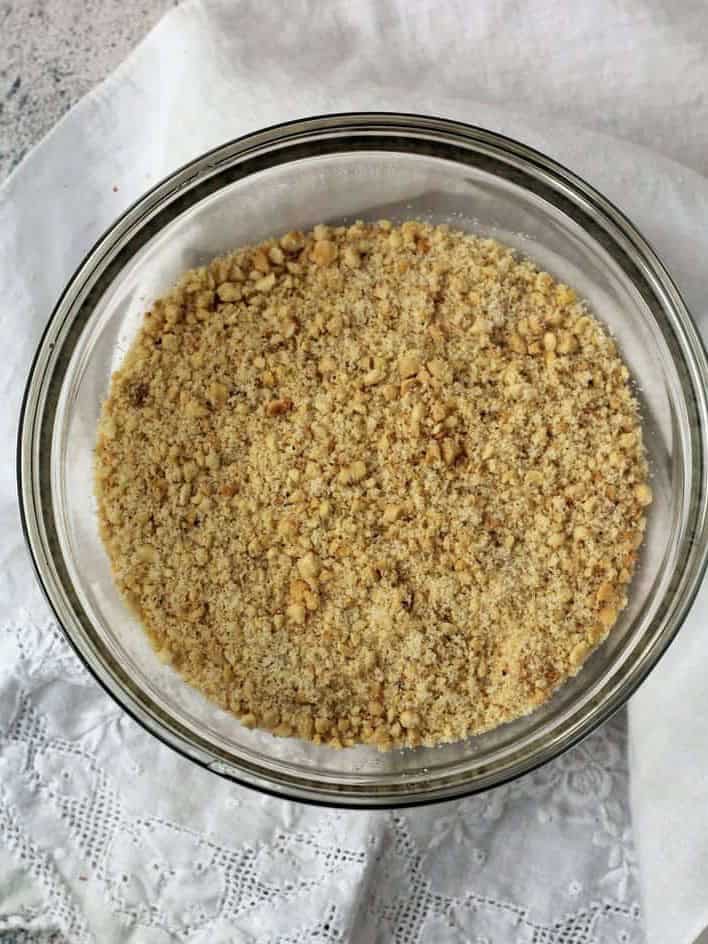 Ground hazelnuts and sugar in glass bowl for hazelnut cookies.