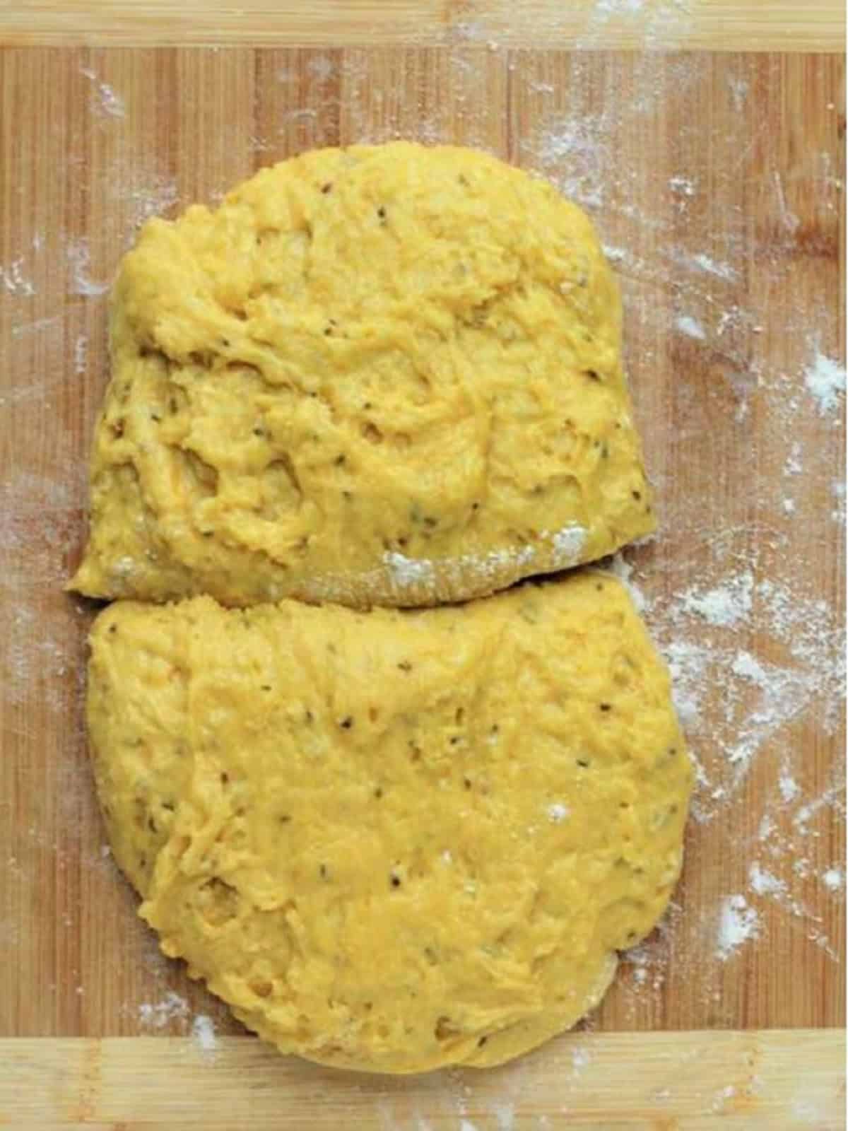 Dough for anise biscotti divided in half on wood board.