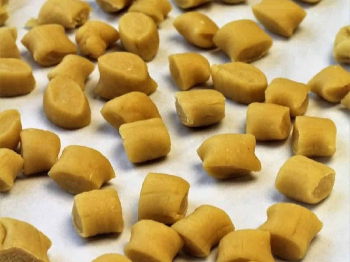 Individual cut pignolata dough pieces on baking sheet.