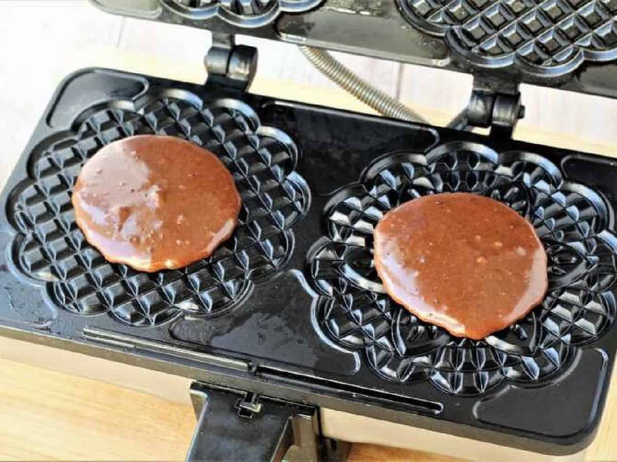 Chocolate pizzelle cookie batter on pizzelle iron.