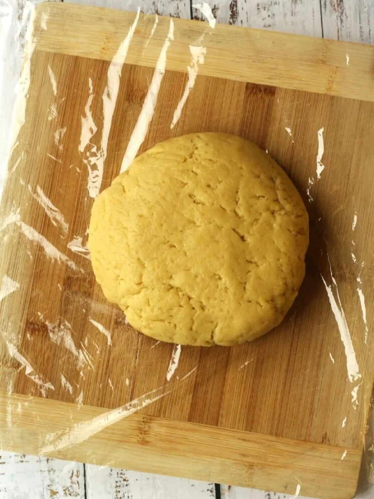 S cookie dough shaped into disc and wrapped in plastic wrap.