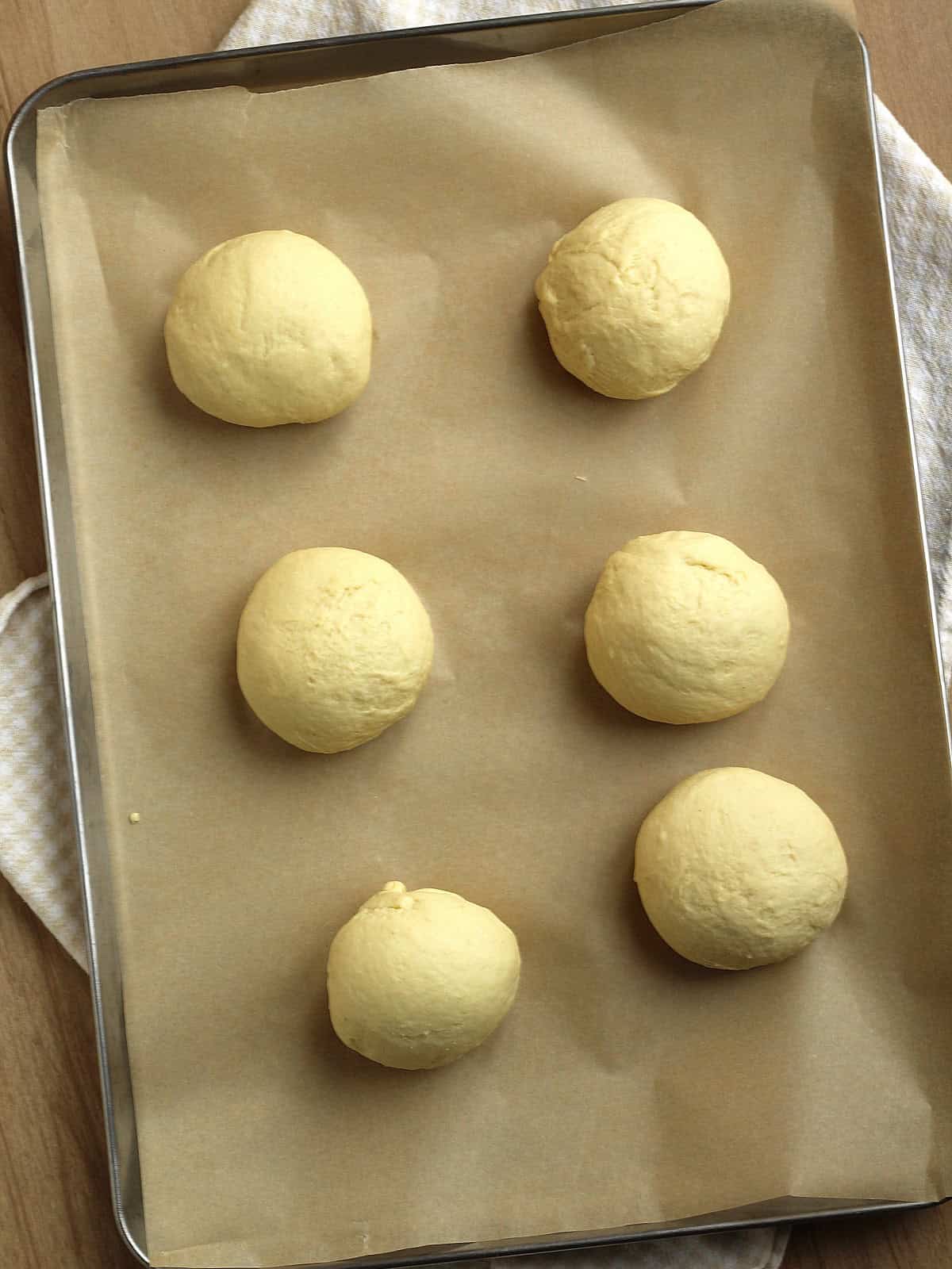 Balls of semolina bread dough on baking sheet.