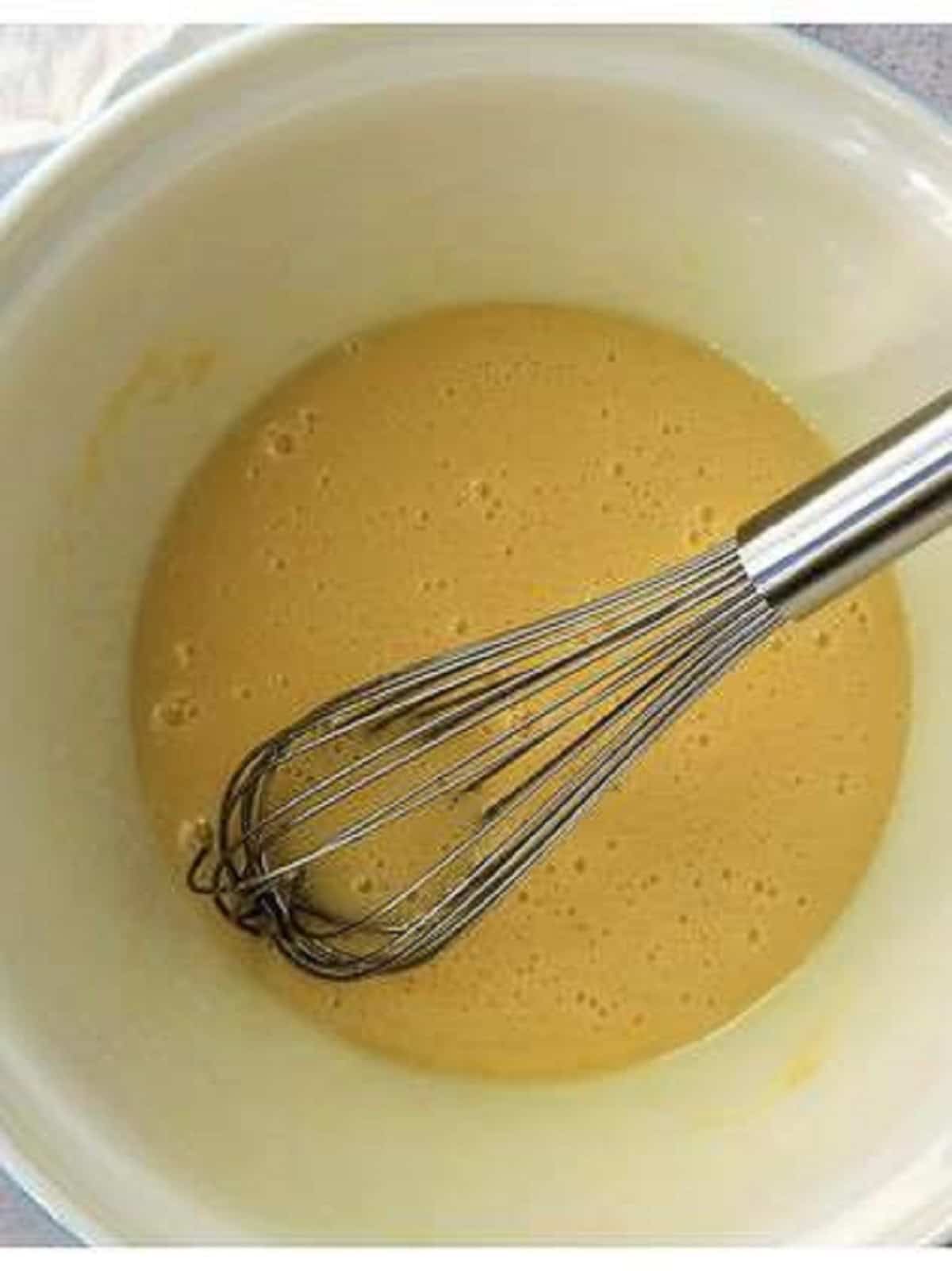 Whisked eggs, sugar and oil in bowl for nut jam rolled cookies.