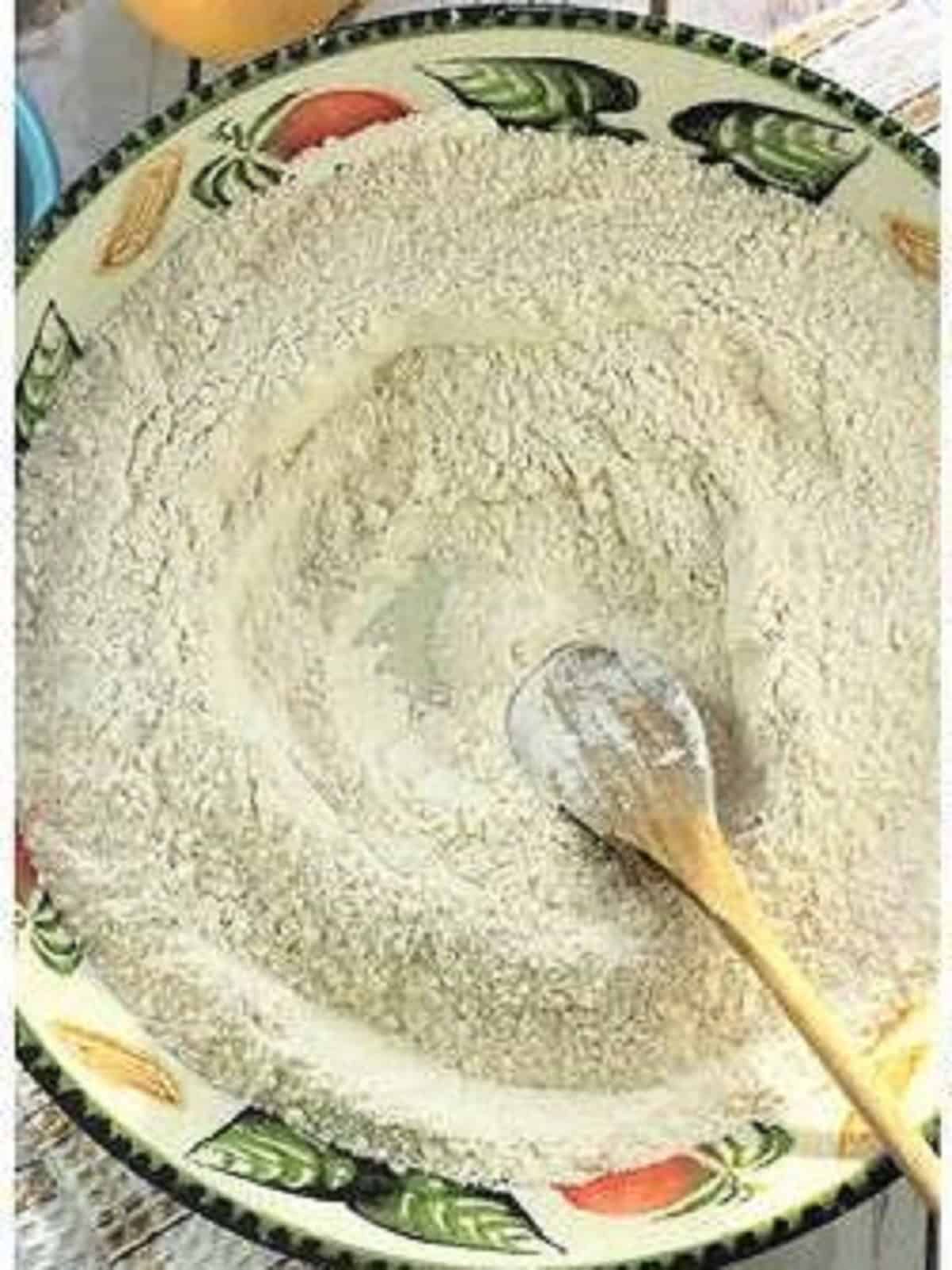 Dry ingredients for chiacchiere recipe stirred together in large bowl with wooden spoon.