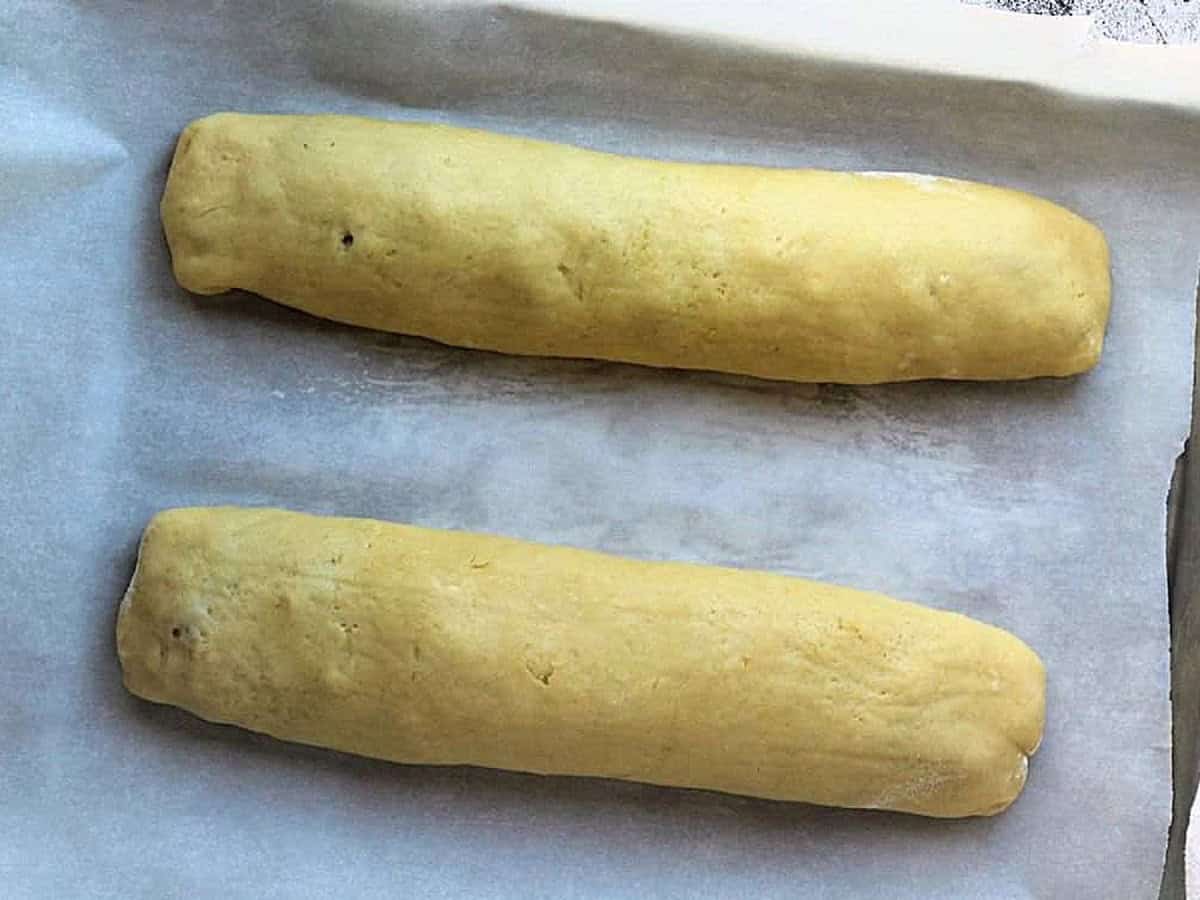 Rolled cookie dough logs filled with nuts and jam on baking sheet.