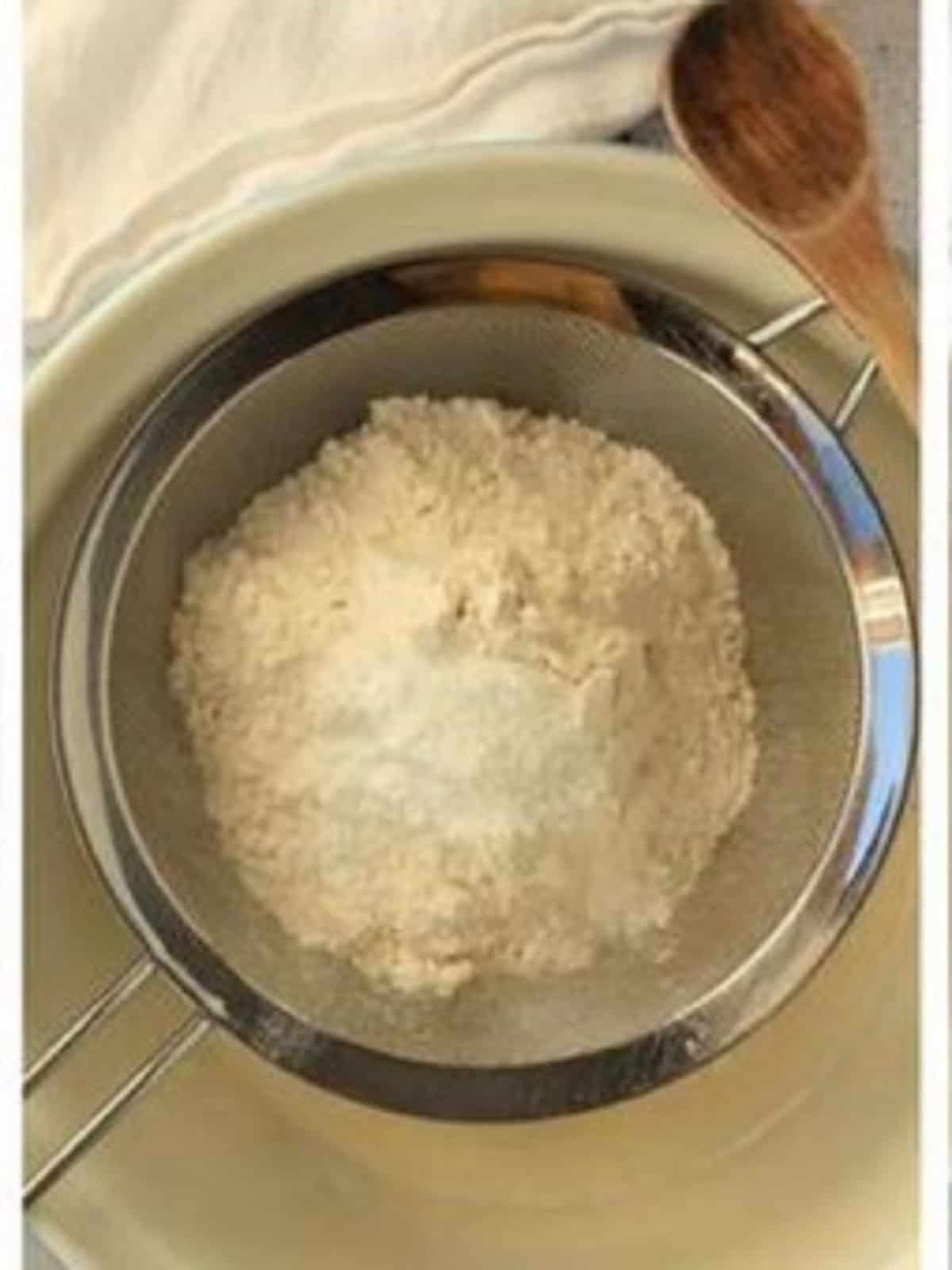 Dry ingredients sifted over bowl with wet ingredients for Italian cookies.