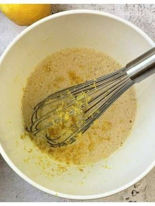 Lemon zest whisked into pizzelle batter in mixing bowl.