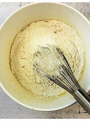 Flour whisked into pizzelle batter in bowl.
