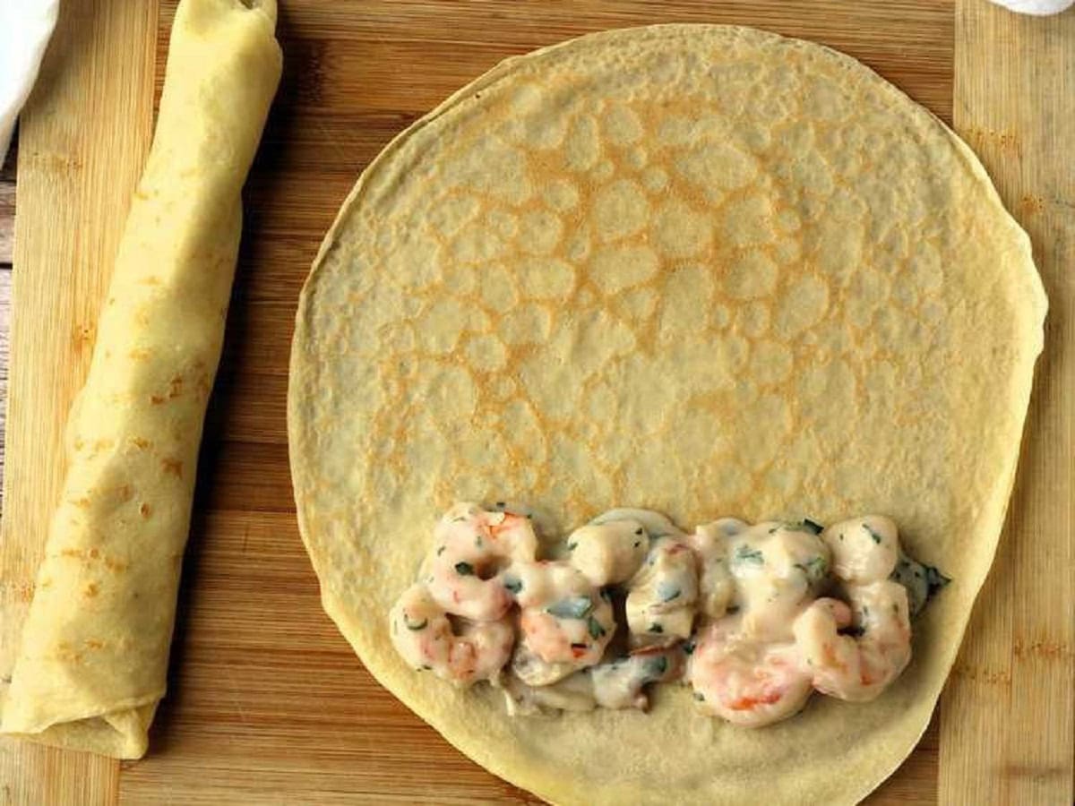 Seafood with bechamel sauce placed on crepe and rolled up.