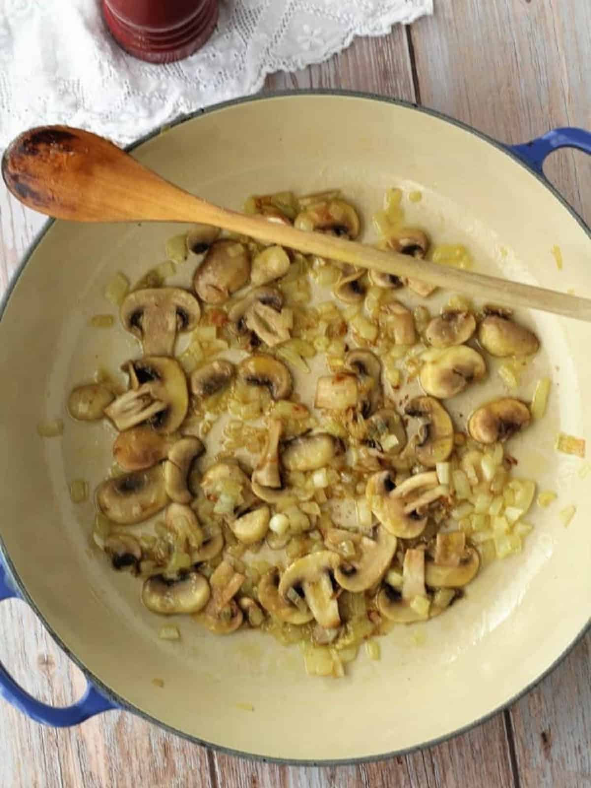 Sautéed onion and miushrooms in skillet for seafood crepe filling.