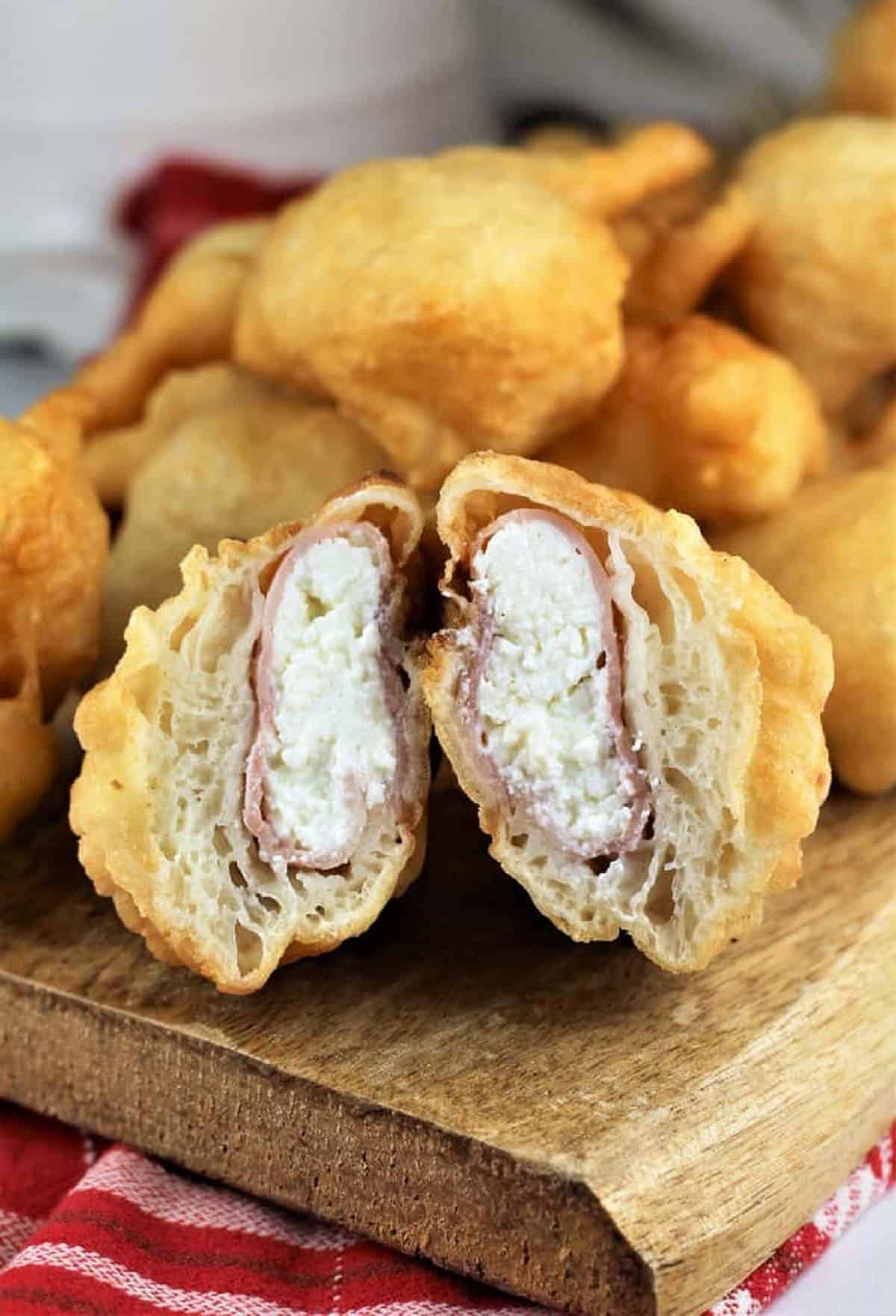 Stuffed sfinci with ricotta and ham cut open on wood board.