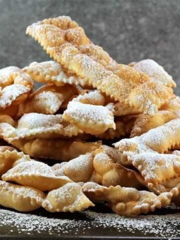 Chiacchiere di Carnevale piled on one another and dusted with powdered sugar.