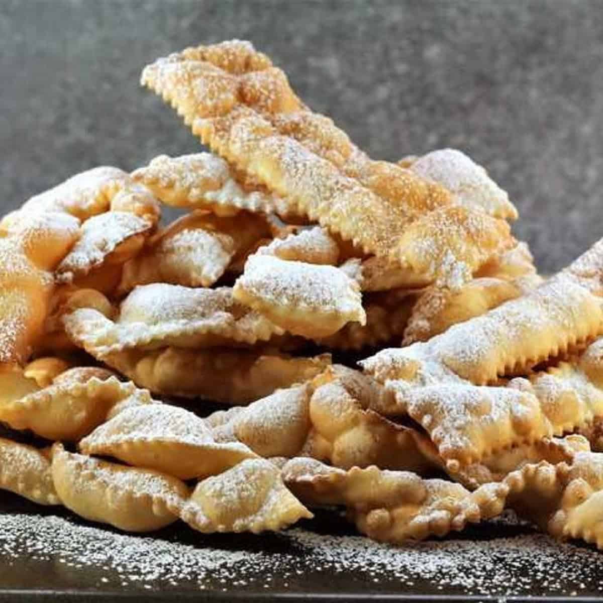 Chiacchiere di Carnevale piled on one another and dusted with powdered sugar.