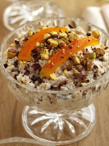 Sicilian cuccia (wheat berry and ricotta pudding) in glass cup topped with candied orange and chopped pistachios.