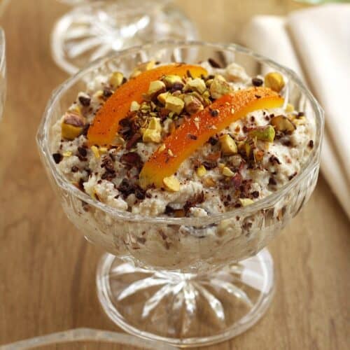 Sicilian cuccia (wheat berry and ricotta pudding) in glass cup topped with candied orange and chopped pistachios.