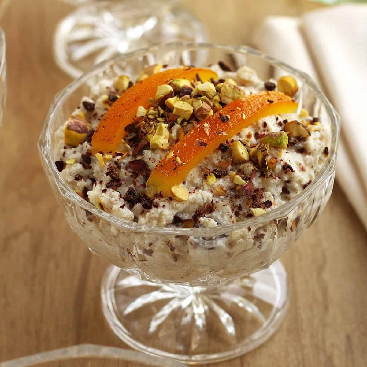 Sicilian cuccia (wheat berry and ricotta pudding) in glass cup topped with candied orange and chopped pistachios.