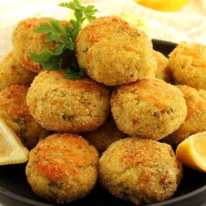 Codfish patties with potatoes piled on plate with parsley sprig and lemon wedge.
