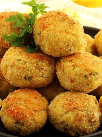 Codfish patties with potatoes piled on plate with parsley sprig and lemon wedge.