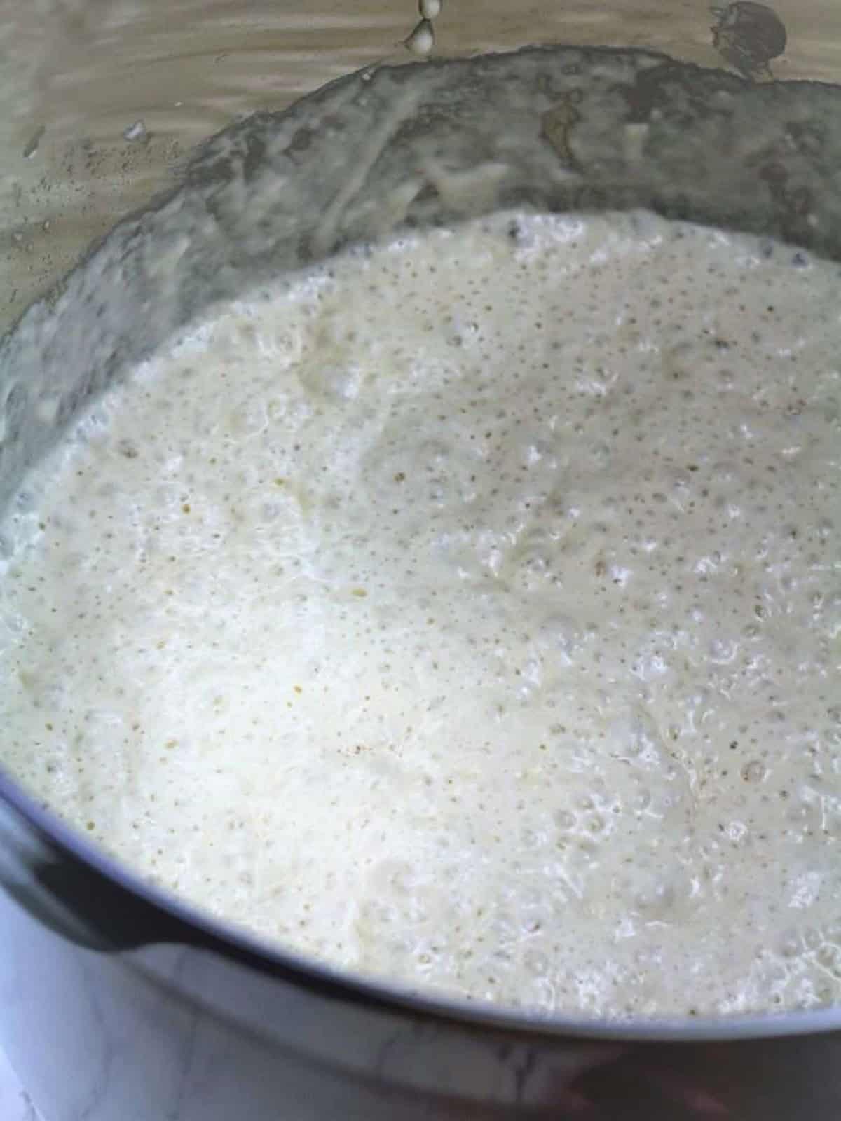 Leavened sfinci dough with bubbles on top in sauce pan.