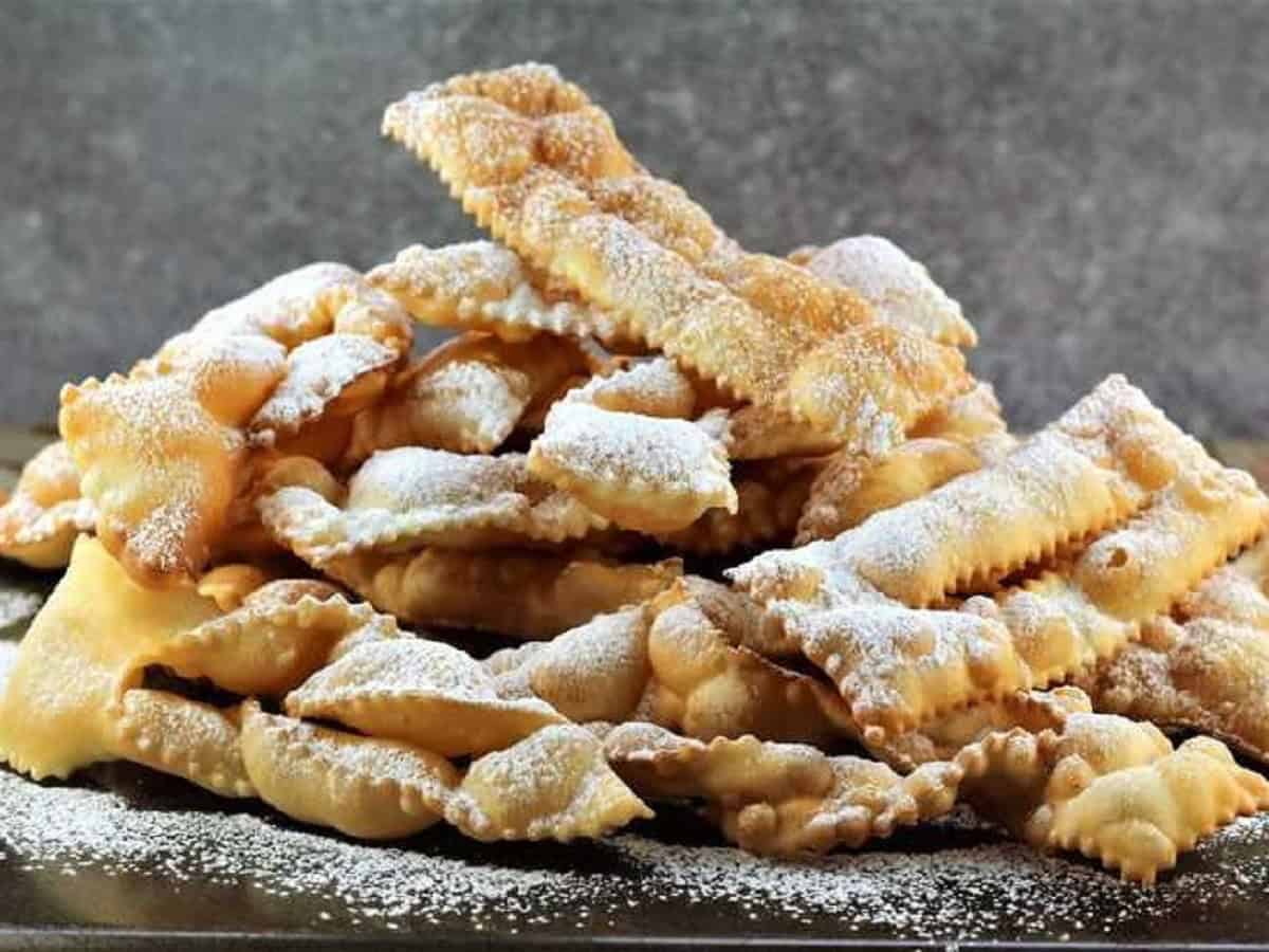 Chiacchiere, strips of sweet fried dough, piled and dusted with powdered sugar.