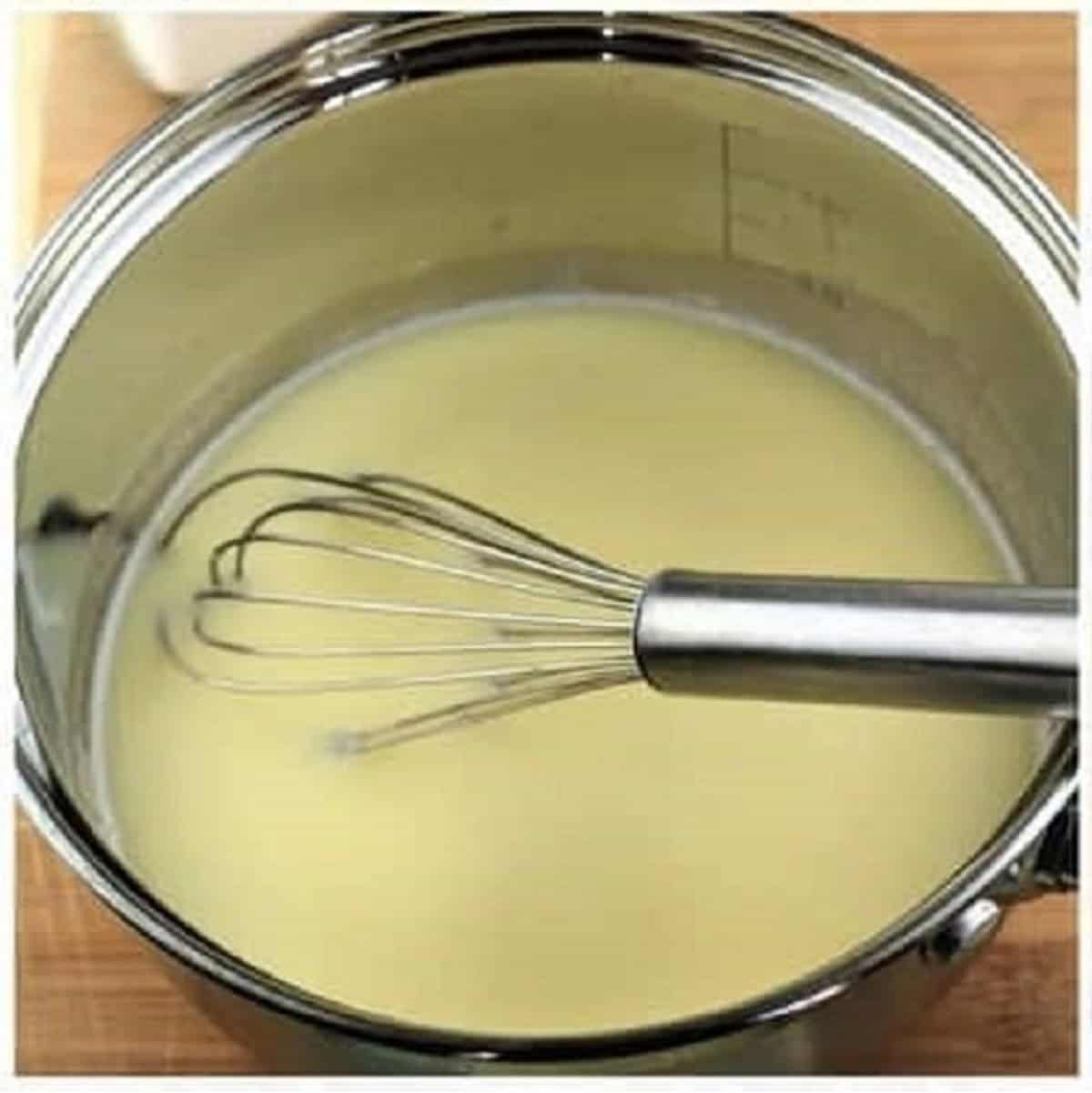 Milk whisked with roux in sauce pan for bechamel sauce.
