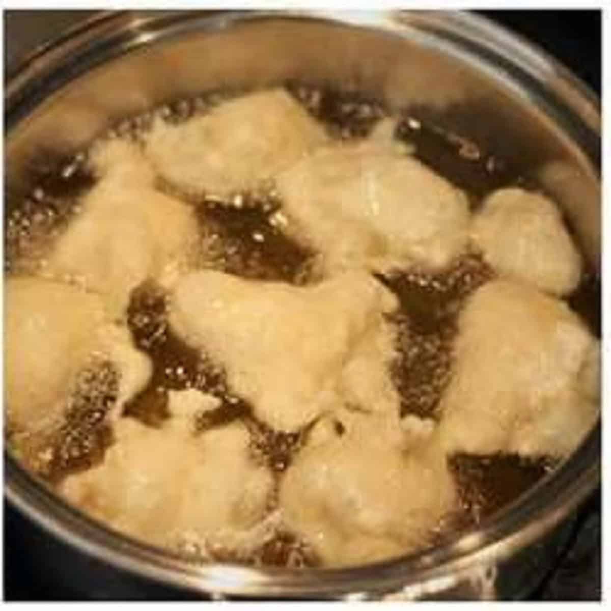 Fried sfingi in pan filled with oil.