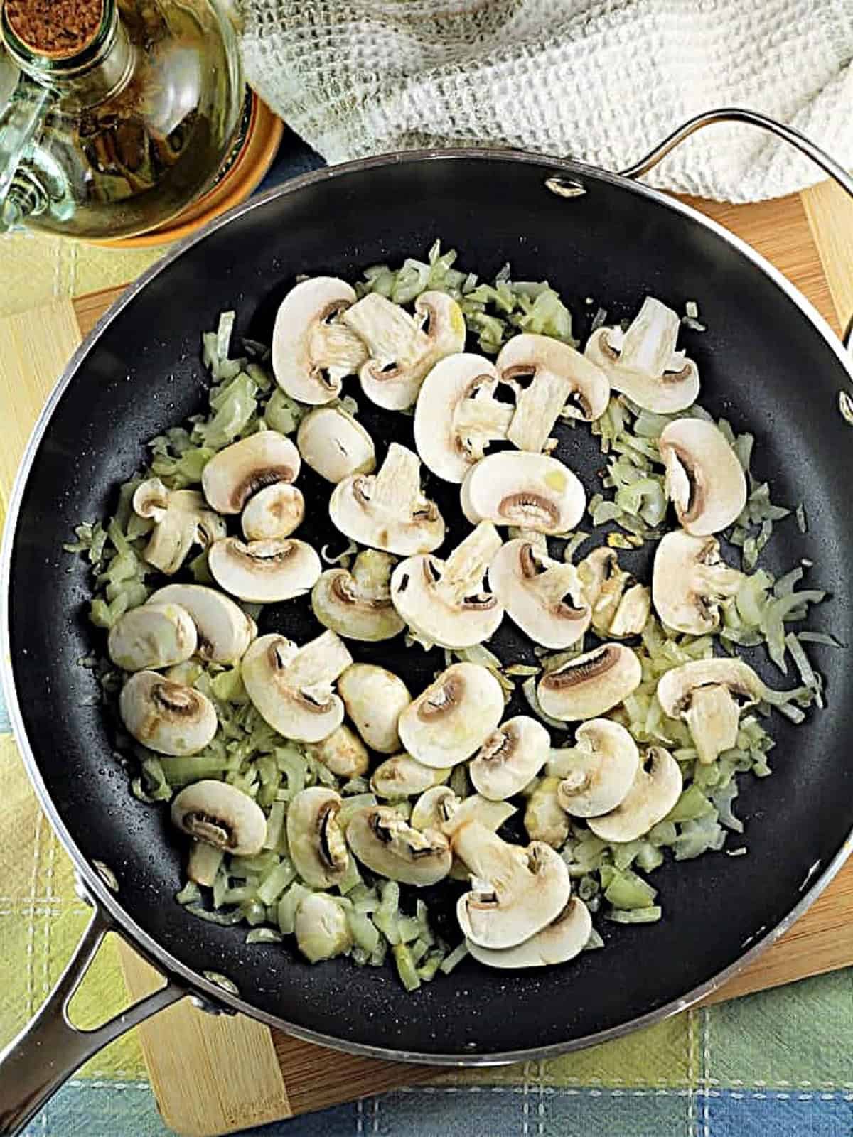 Mushrooms and onions sautéed in skillet for coquilles St-Jacques.